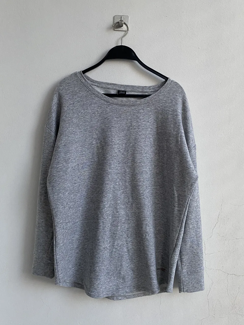 Buzo de cuello redondo para mujer, de color gris. Diseño con espalda descubierta, ideal para un look casual y moderno. Perfecto para combinar con jeans.