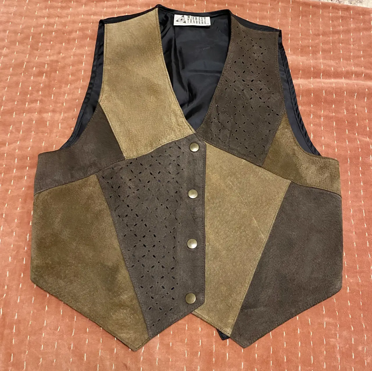 Chaleco de cuero gamuzado con diseño patchwork en tonos marrones y detalles calados. Cierre con botones y forro interior.