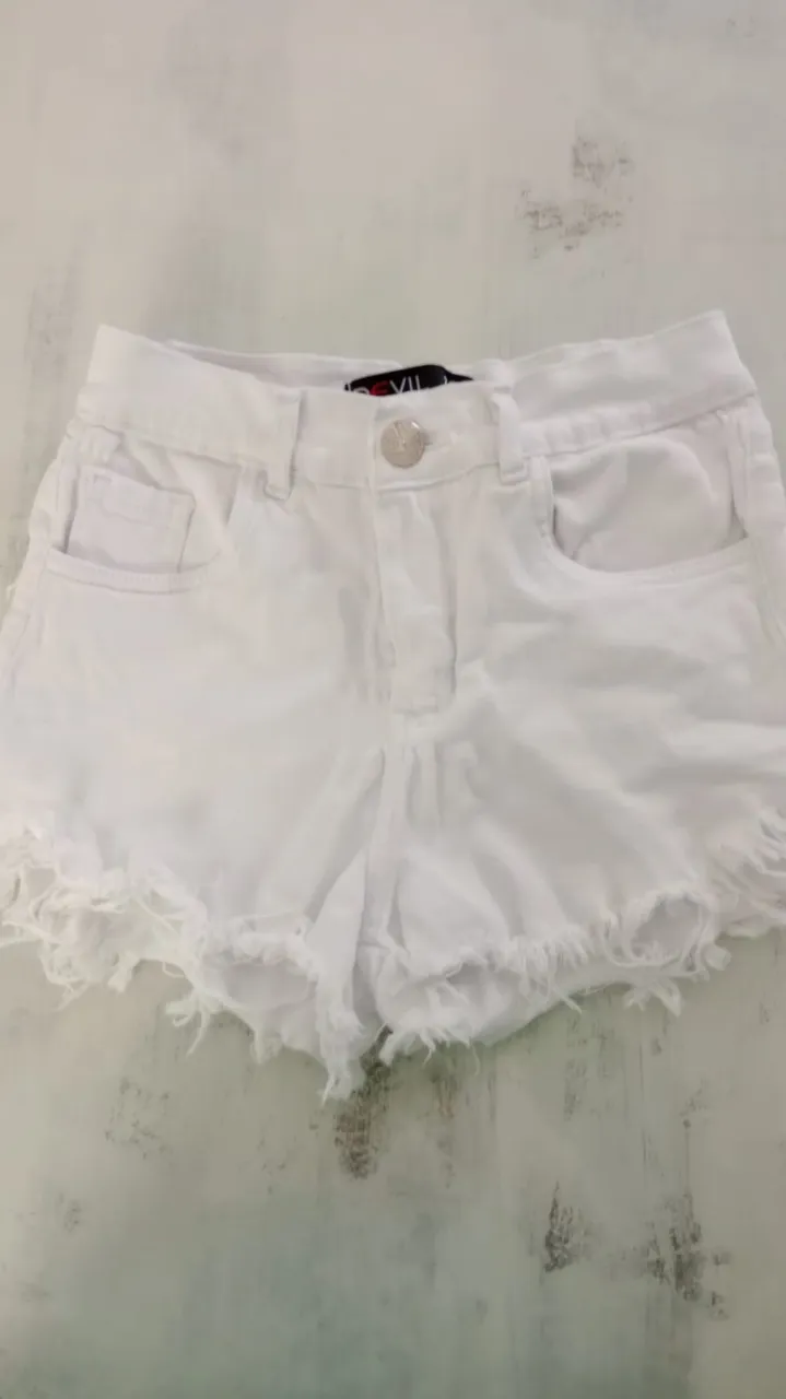 Shorts de jean blancos con roturas y flecos en el ruedo. Tiro alto, con bolsillos y detalles desgastados.