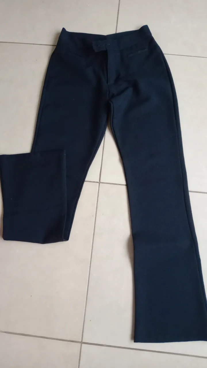 Pantalón de vestir negro, tiro alto, con corte acampanado. Ideal para un look elegante y formal.
