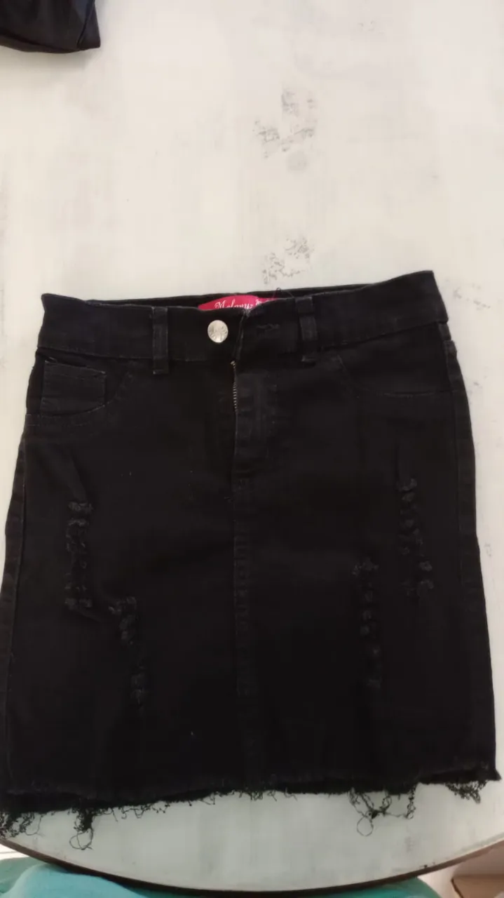 Pollera de jean negra, tiro alto, con roturas y terminación deshilachada. Un básico canchero para armar looks informales.