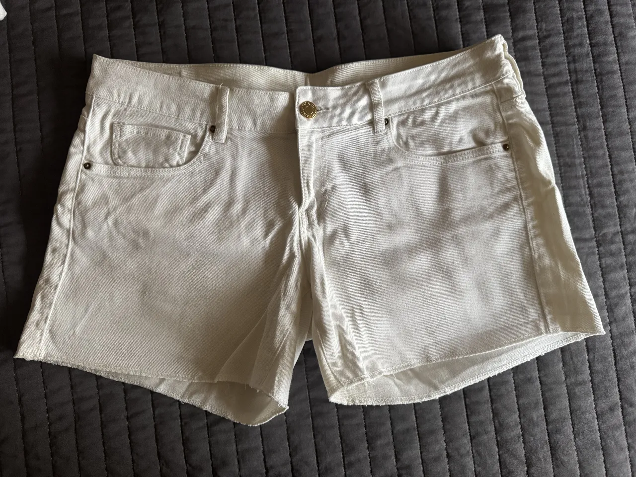 Short de jean blanco, tiro bajo, con roturas desflecadas en el ruedo. Perfectos para un look casual de verano.