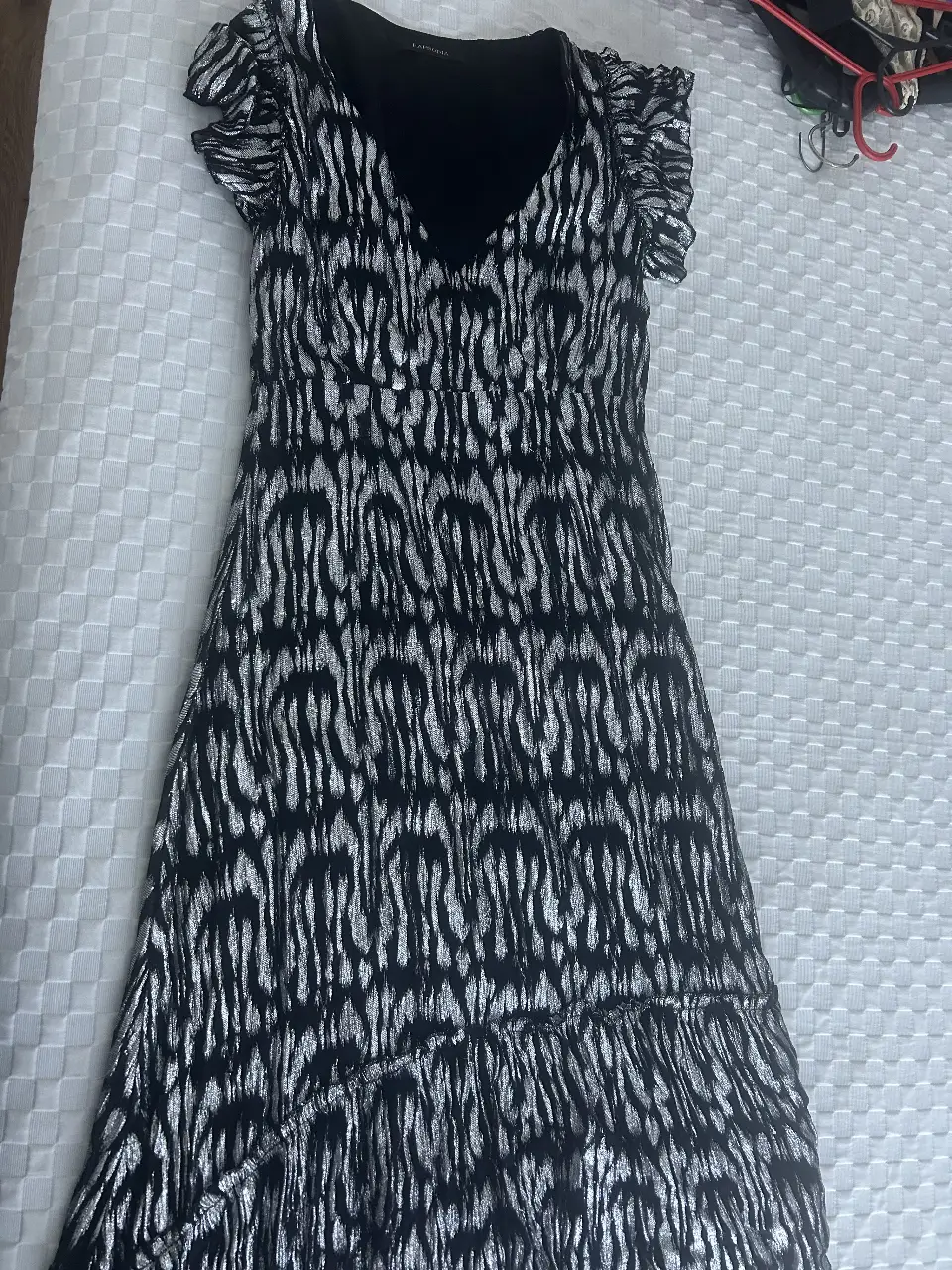 Vestido midi con estampado de cebra en tonos plateados y negros. Diseño elegante con escote en V y mangas cortas con volados. Ideal para eventos especiales o salidas nocturnas.