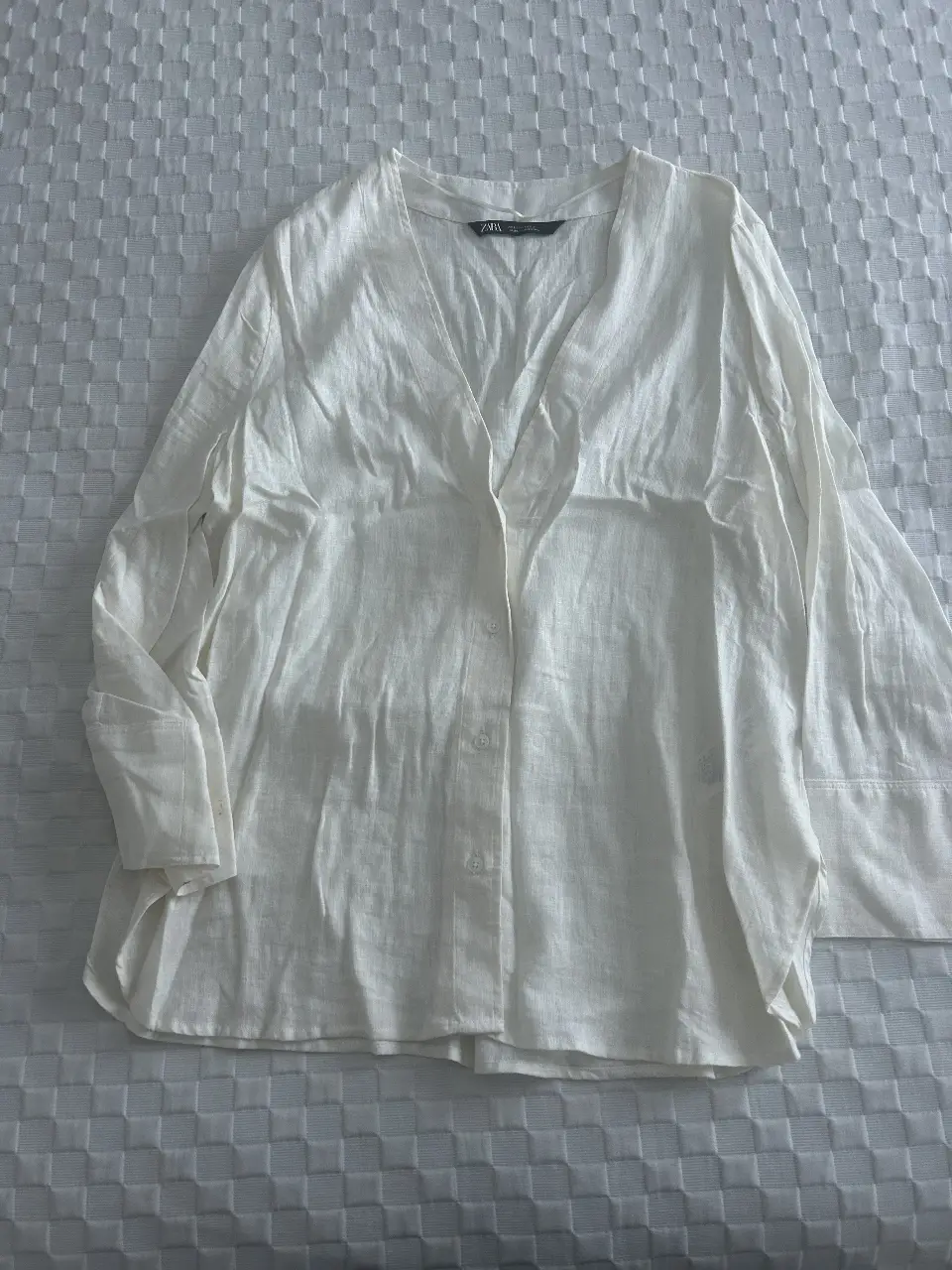 Blusa blanca de lino con cuello en V y mangas largas. Ideal para un look casual y fresco.