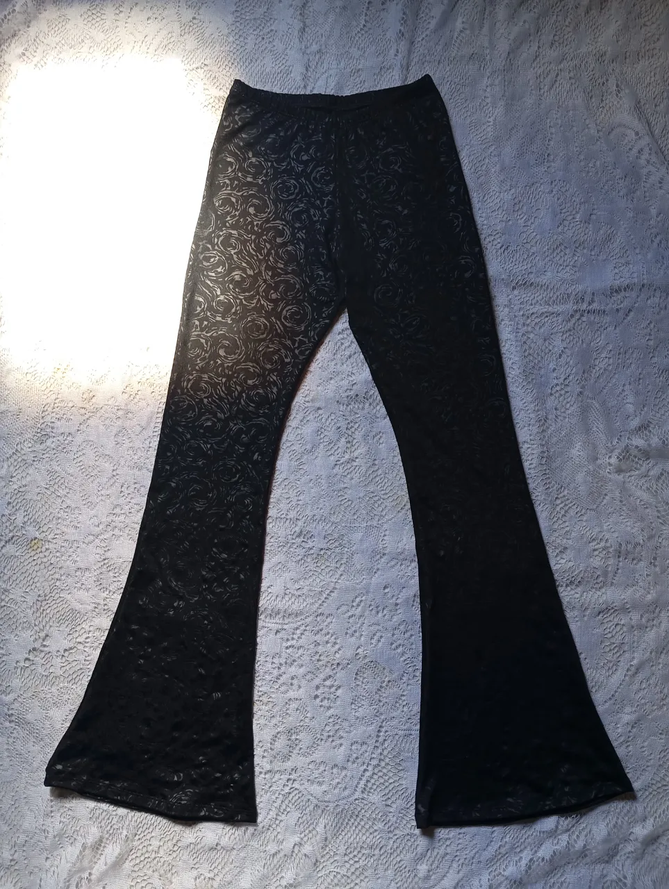 Calza Oxford negra con estampado de rosas en relieve. Piernas acampanadas.