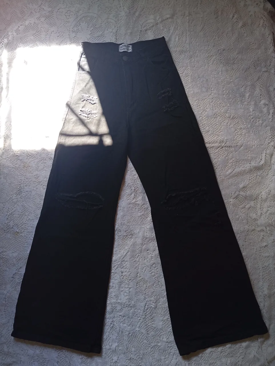 Pantalón de jean negro con roturas.