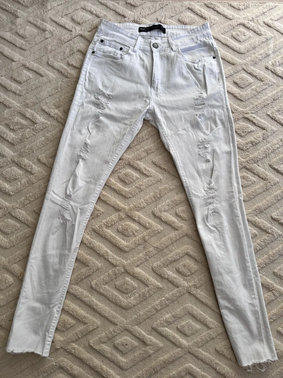 Jeans blancos tiro alto, corte skinny, con roturas y detalles deshilachados en los bajos. Un básico canchero para cualquier look.