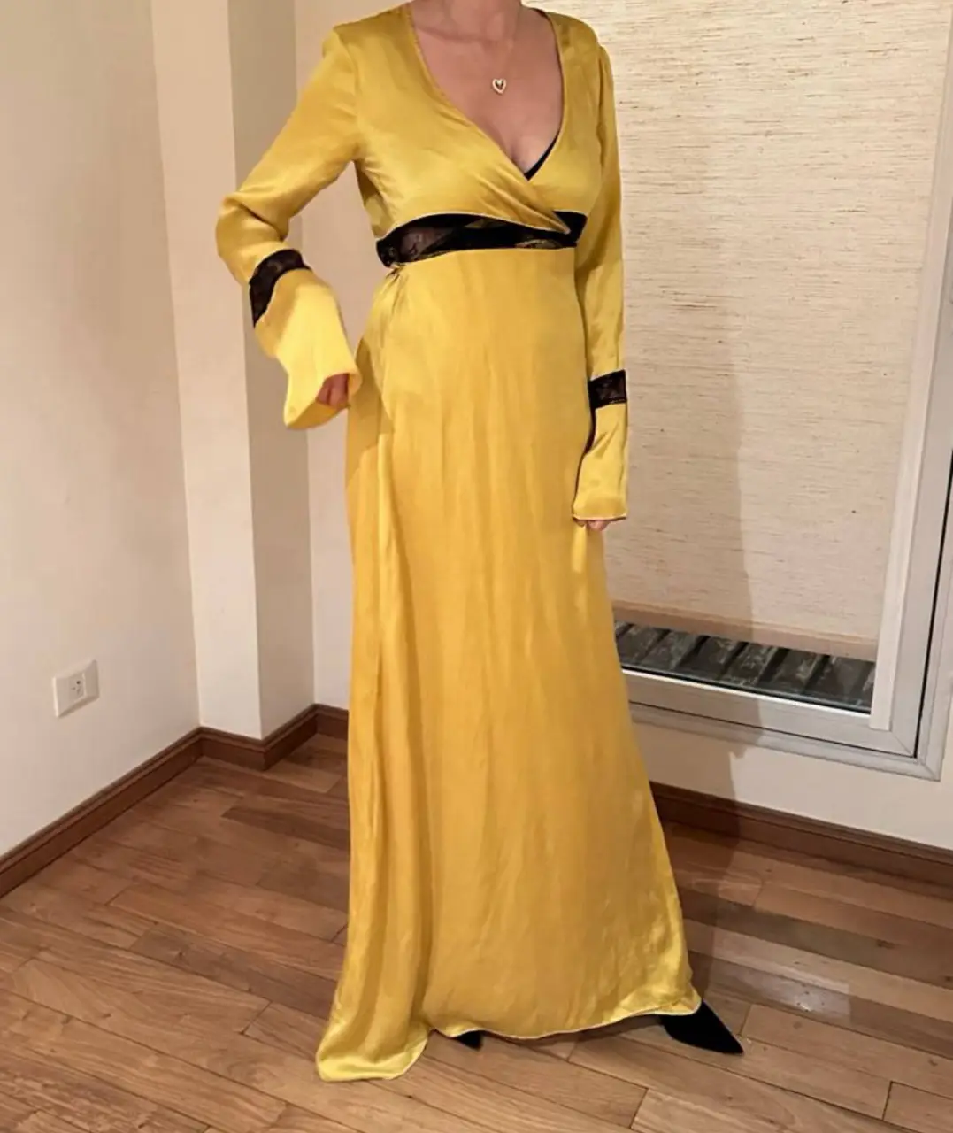 Vestido largo de fiesta en color amarillo, con detalles en negro. Posee mangas largas con volados y un corte en la cintura con encaje negro. La espalda tiene un diseño con transparencias.