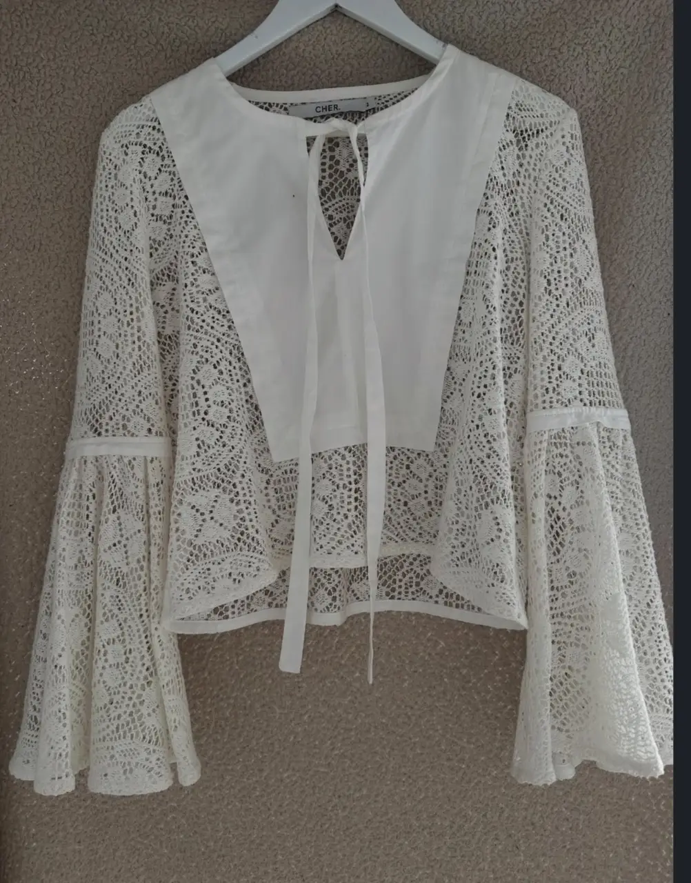 Blusa de encaje blanca con mangas acampanadas. Ideal para un look bohemio y elegante. Perfecta para combinar con jeans o faldas.
