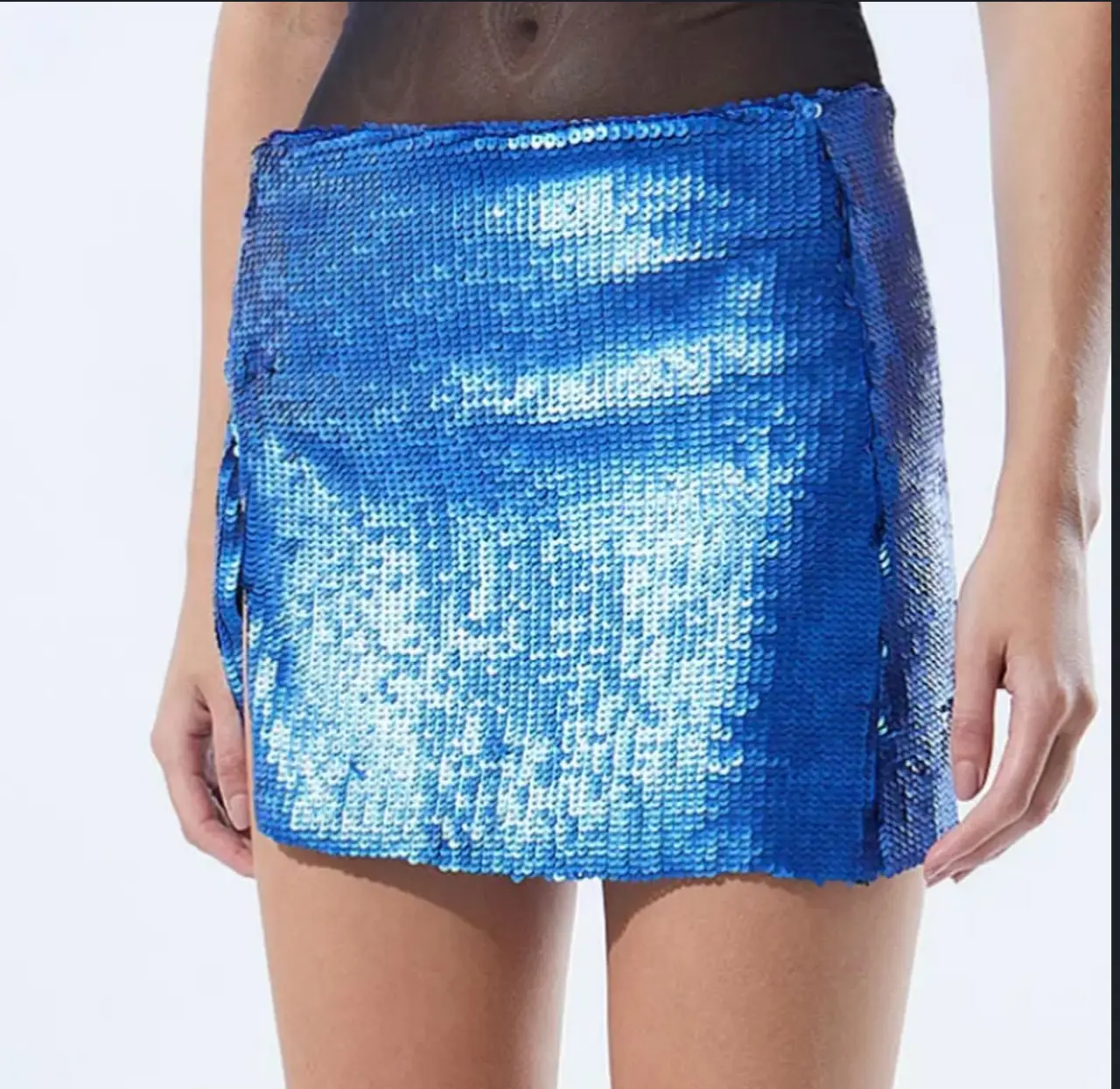 Minifalda de lentejuelas azul brillante, ideal para fiestas y eventos especiales. Diseño con detalles laterales y abertura que le dan un toque moderno y audaz.