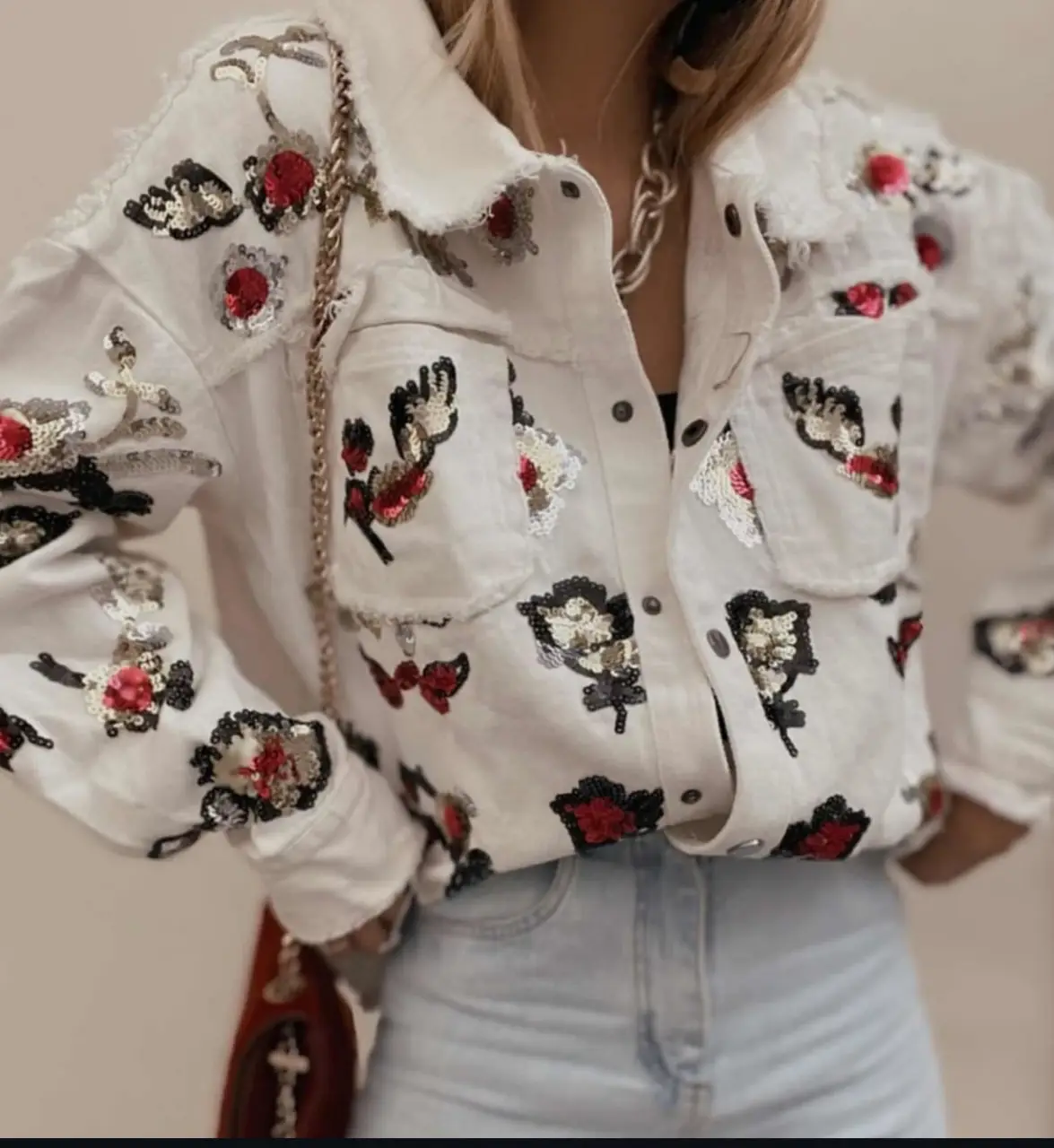 Campera de jean blanca con apliques de lentejuelas rojas y plateadas. Estilo único y llamativo, ideal para darle un toque especial a cualquier outfit.
