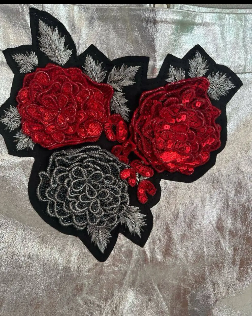 Minifalda plateada de cuero con aplique de flores bordadas en rojo y negro. Ideal para un look de fiesta o salida.