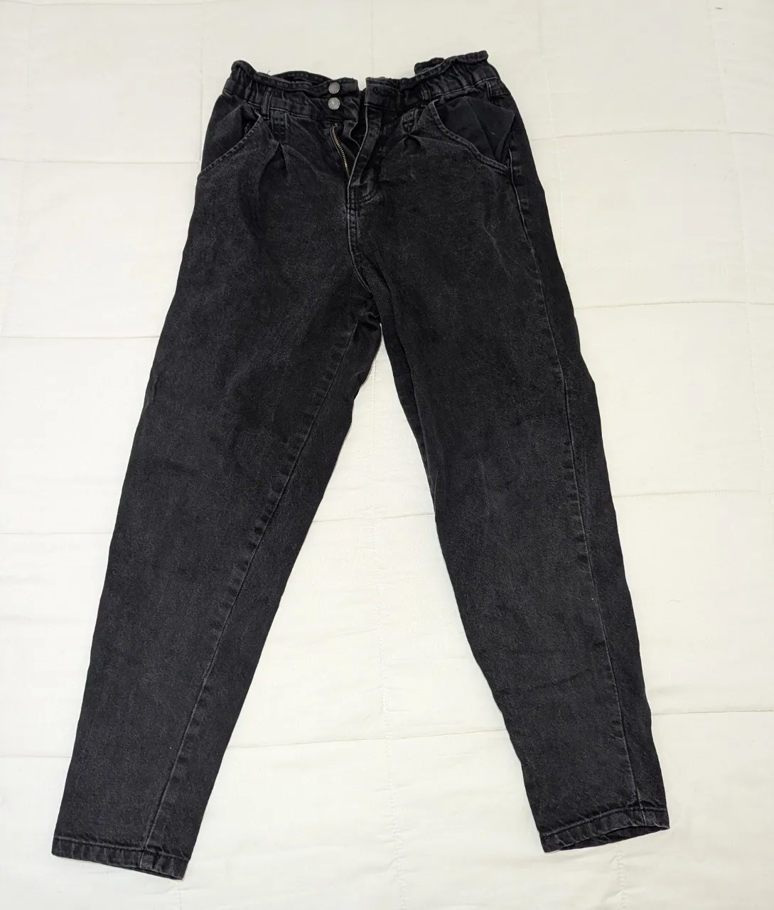 Jean negro con cintura elastizada y detalle de frunces en la parte superior. Posee bolsillos delanteros y traseros.