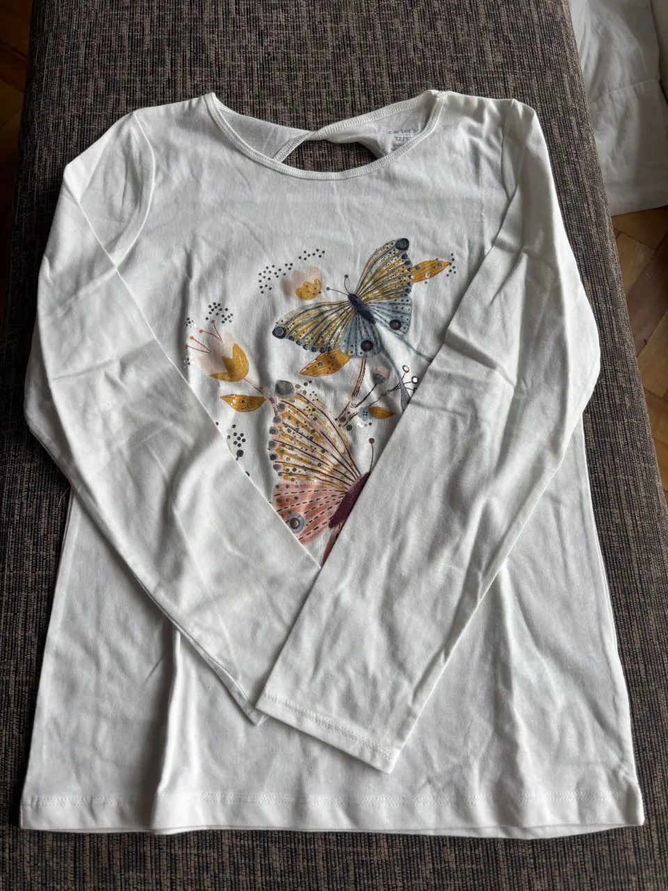 Remera blanca de manga larga con un hermoso estampado de mariposas y flores. Tiene un detalle de corte en la espalda que la hace única y canchera.