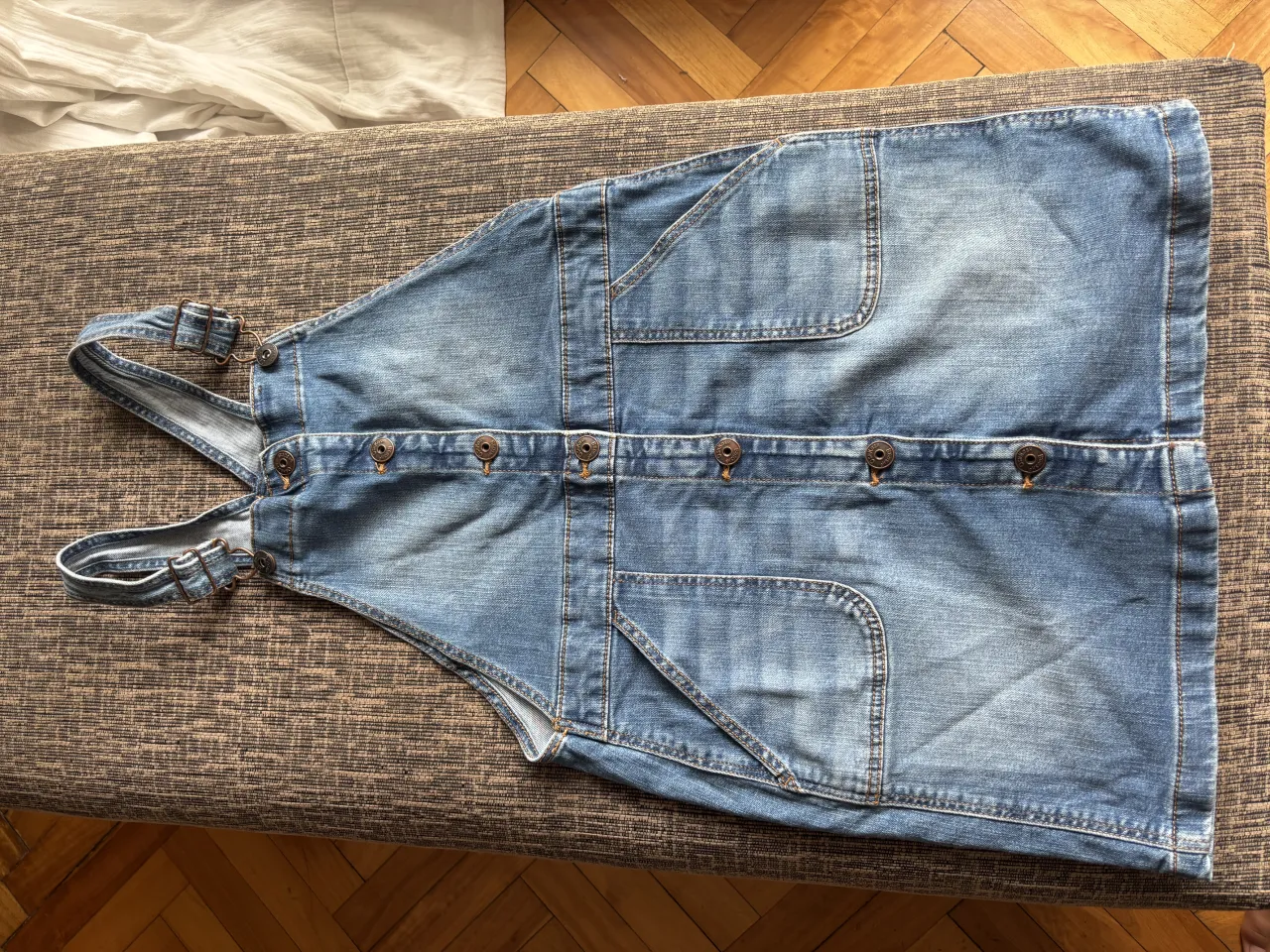 Vestido de jean estilo jardinero, con botones al frente y bolsillos amplios. Ideal para un look casual y cómodo.