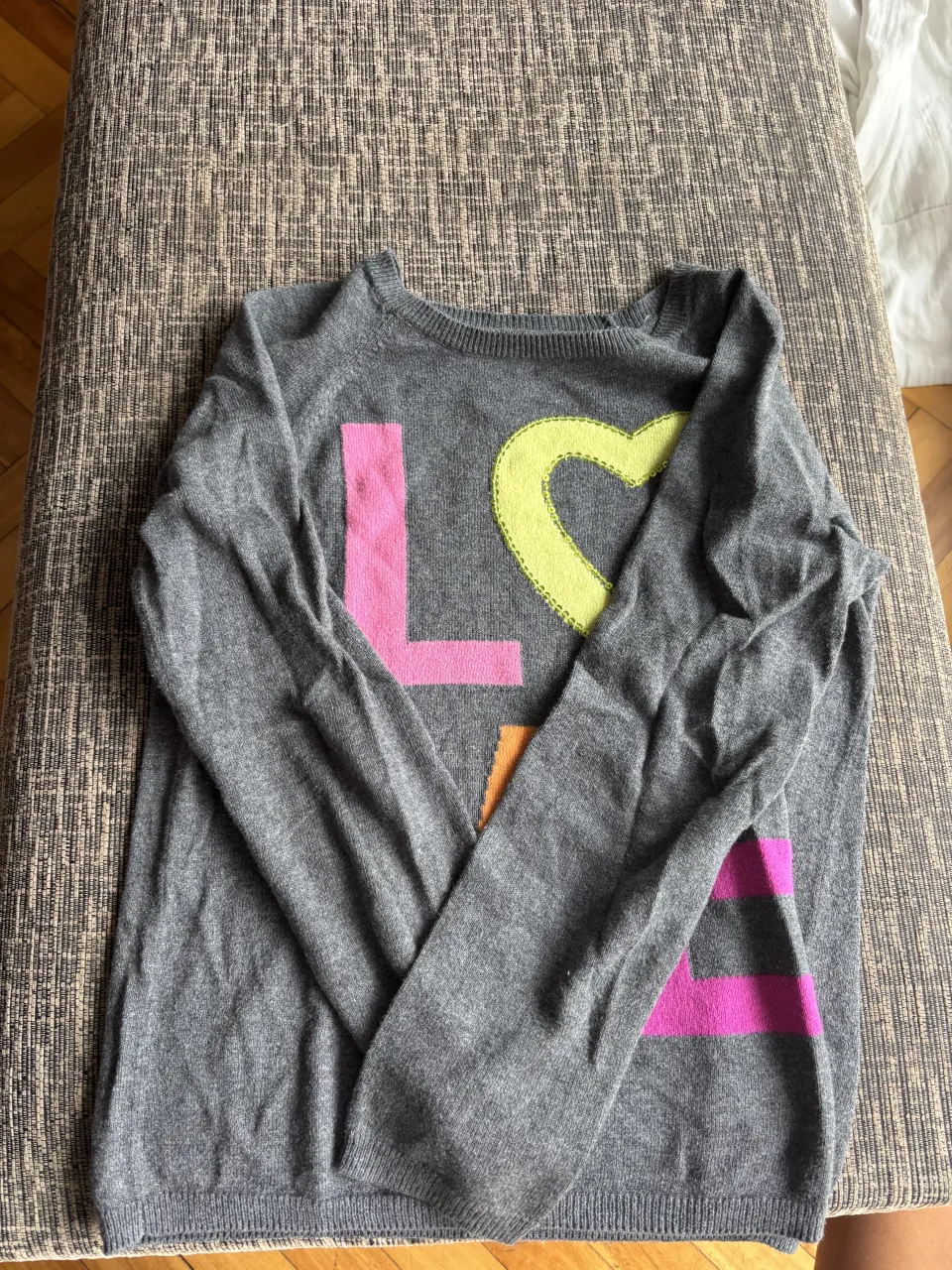 Sweater gris con estampa de letras y corazón en colores vibrantes. Ideal para un look casual y divertido.