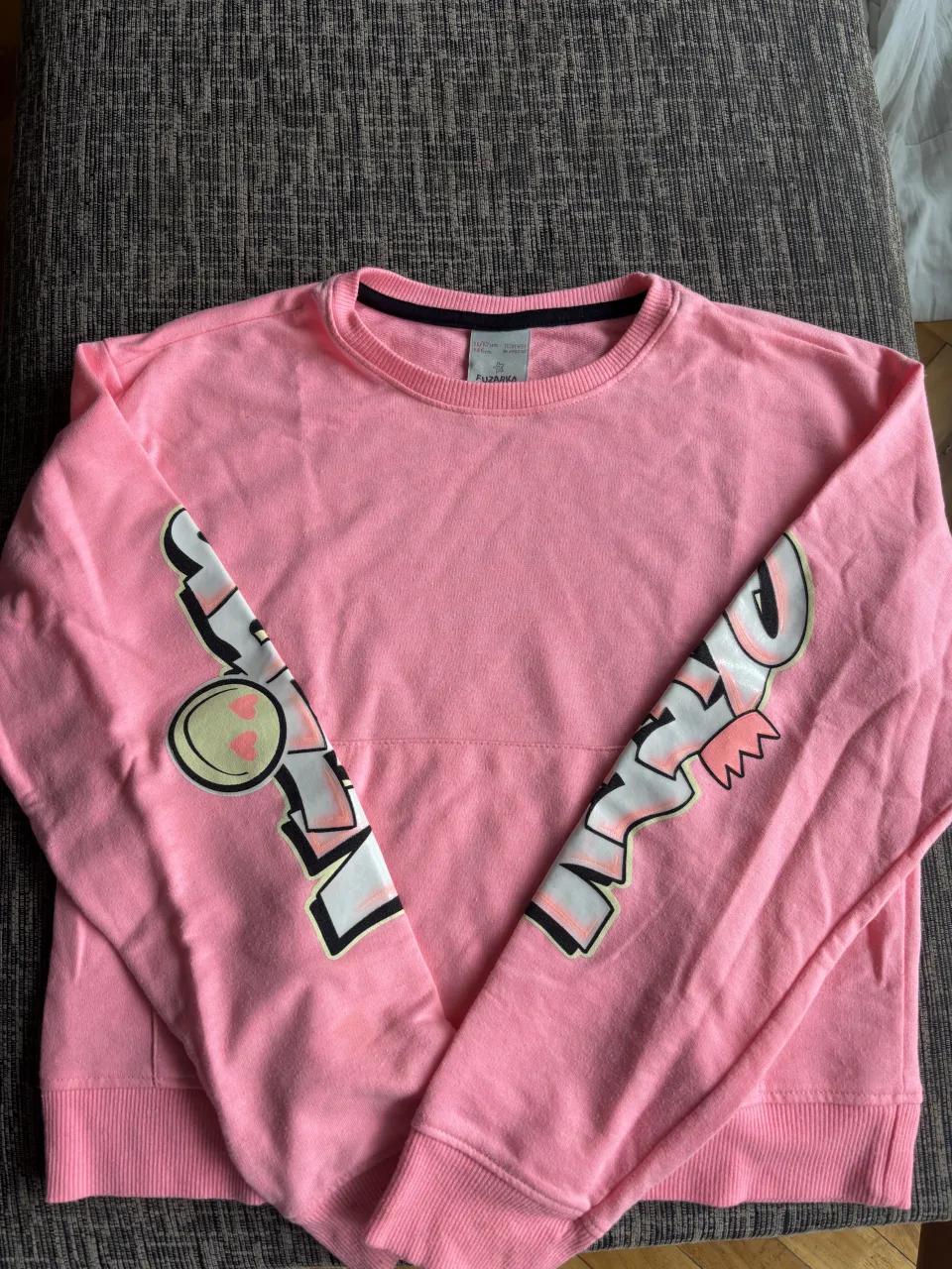 Buzo rosa con estampa divertida en las mangas. Ideal para un look casual y canchero.