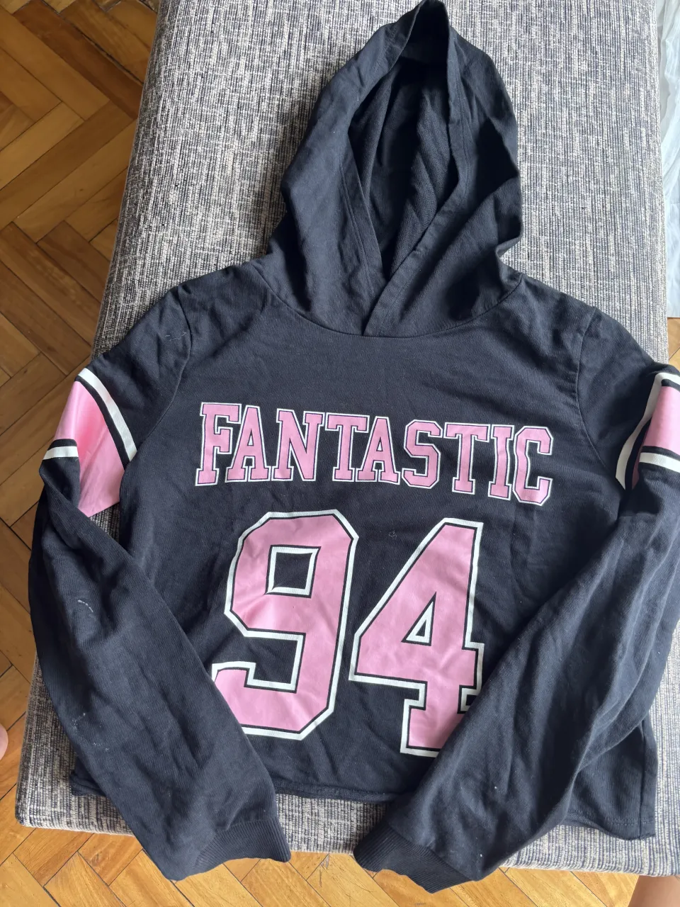 Buzo crop negro con estampa "FANTASTIC 94" en rosa y detalles en las mangas. ¡Un básico canchero para tu día a día!