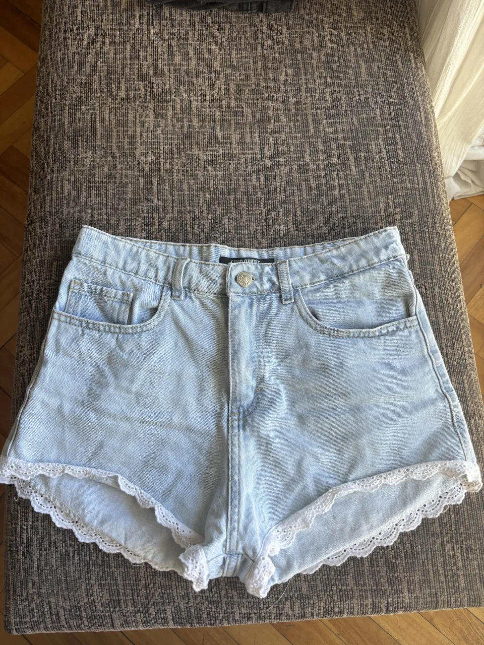 Shorts de jean tiro alto, con detalles de encaje blanco en los bordes. Lavado celeste claro, ideales para un look casual de verano. Talle 30.