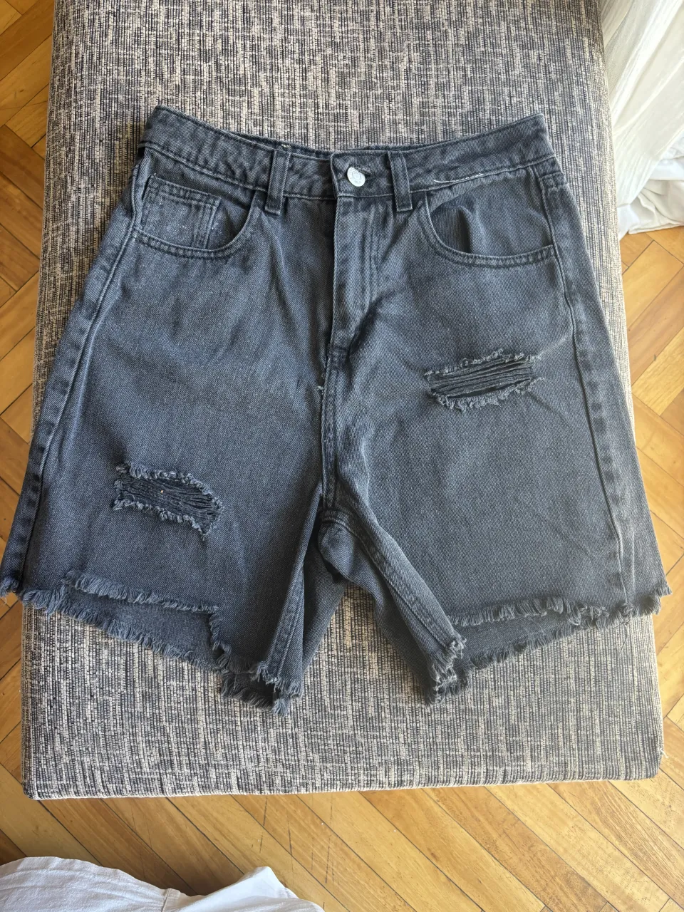 Bermuda de jean negra con roturas y detalles desflecados en los bordes. Un básico súper canchero para armar looks informales y modernos. Talle 30
