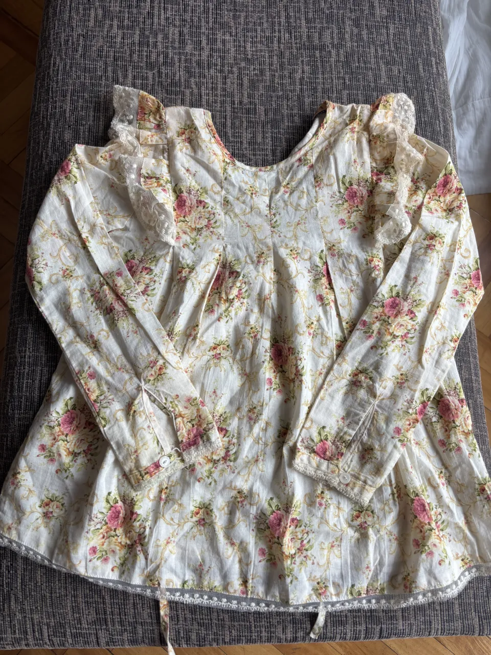 Blusa romántica con estampa floral vintage. Posee mangas largas con detalles de encaje en los hombros y puños. Ideal para un look delicado y femenino.