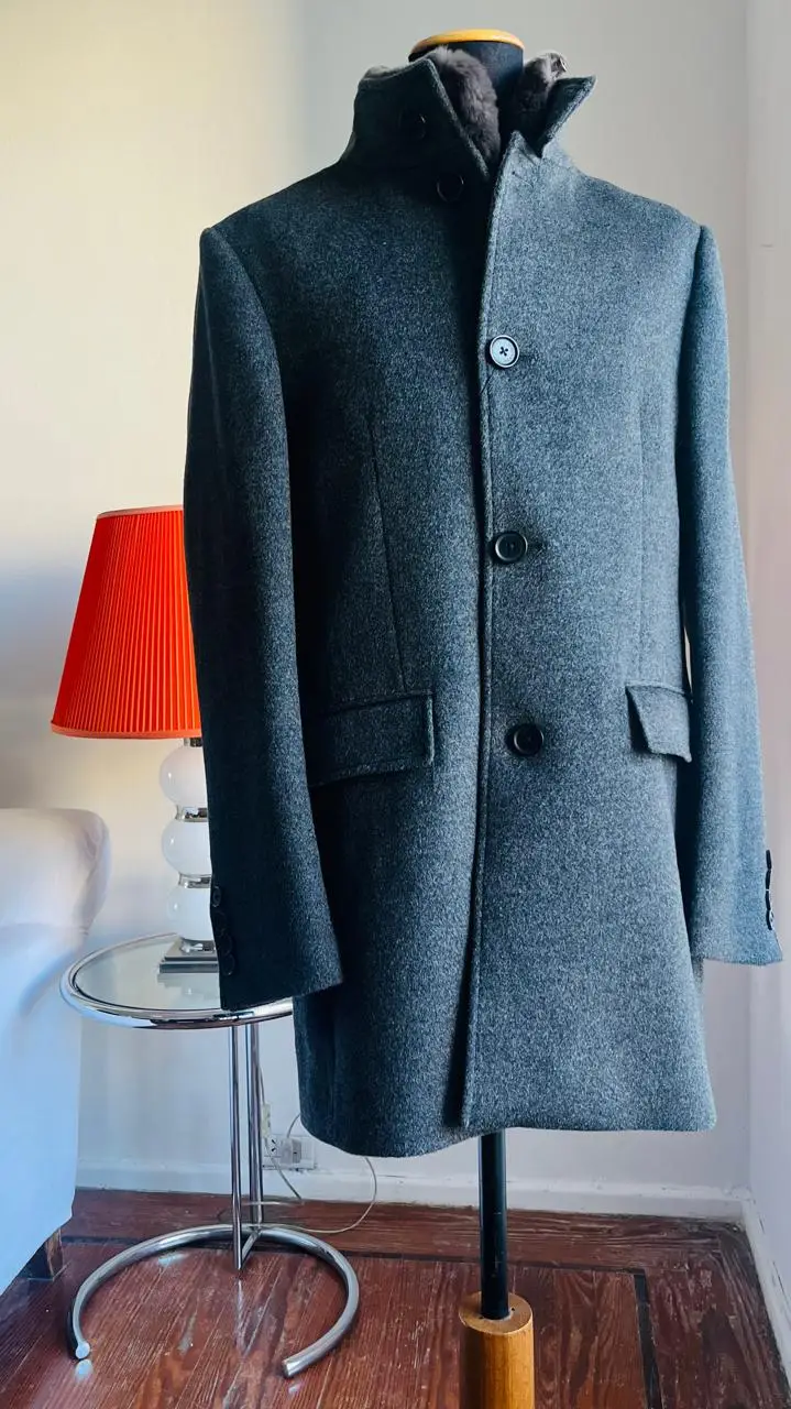 Sobretodo de hombre gris melange, estilo clásico y elegante. Confeccionado en paño de alta calidad, ideal para el invierno. Posee cuello alto y cierre con botones. Perfecto para un look formal o casual sofisticado.