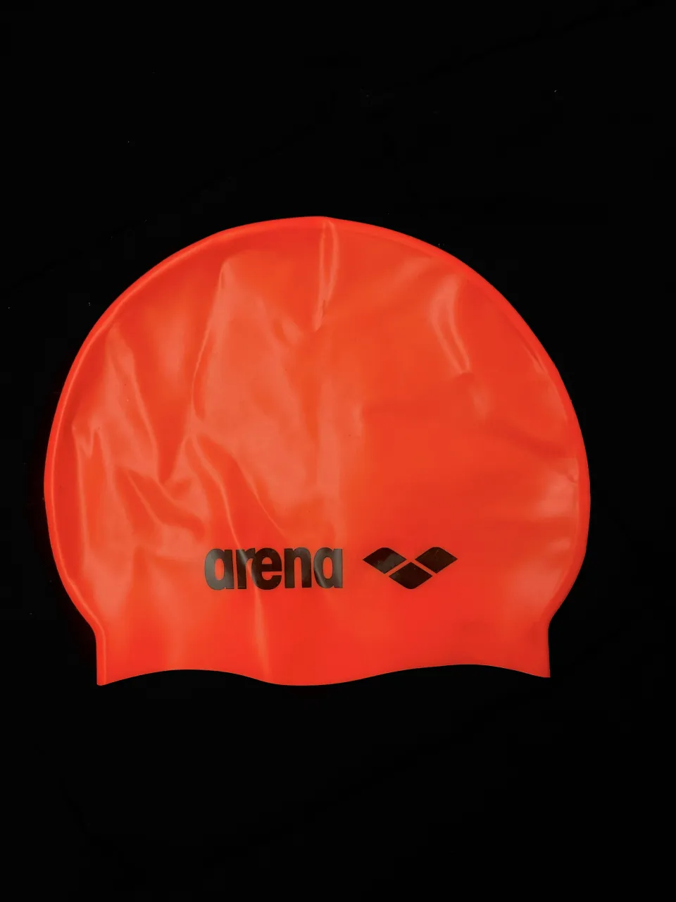 Gorro de natación de silicona color naranja con logo negro de la marca Arena.