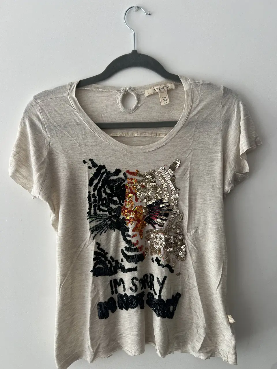 Remera de mujer Kosiuko, color crudo con estampado de tigre con lentejuelas. Talle 40. Ideal para un look casual y canchero.