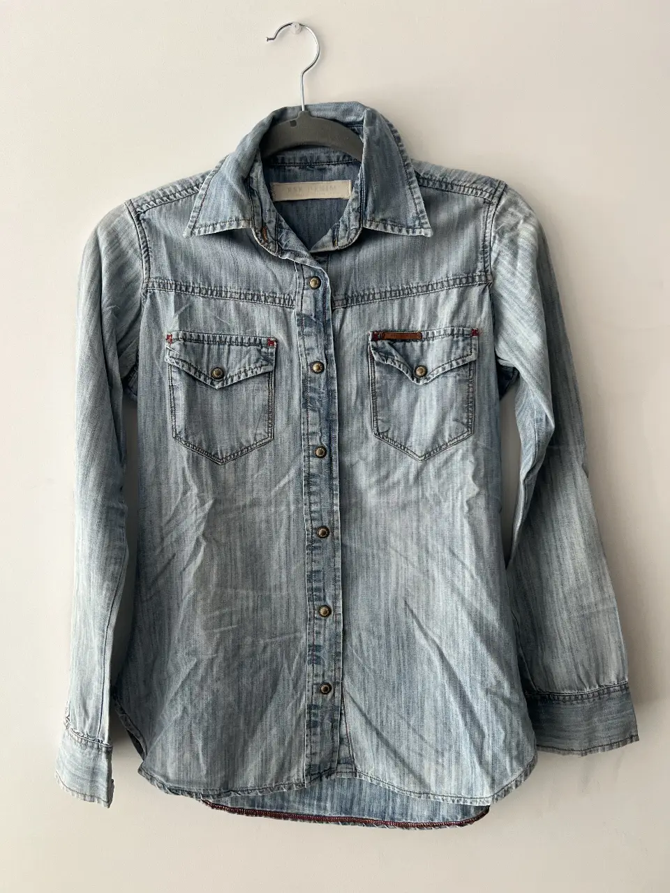 Camisa de jean celeste, con dos bolsillos delanteros y botones. Ideal para un look casual y versátil.
