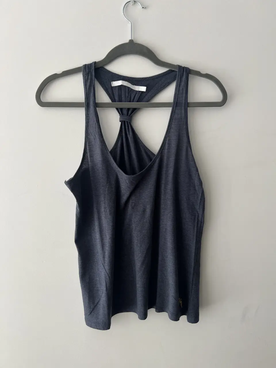 Musculosa de mujer, color azul con detalle de nudo en la espalda. Logo dorado en la parte inferior.
