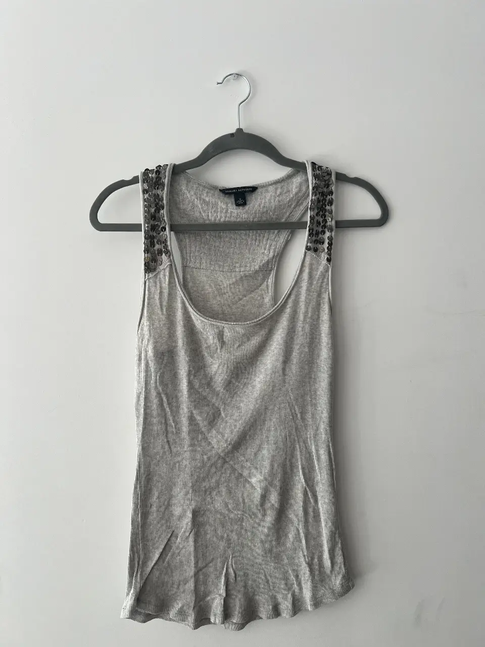 Musculosa gris con detalles de lentejuelas en los hombros y espalda. Ideal para un look casual y moderno.