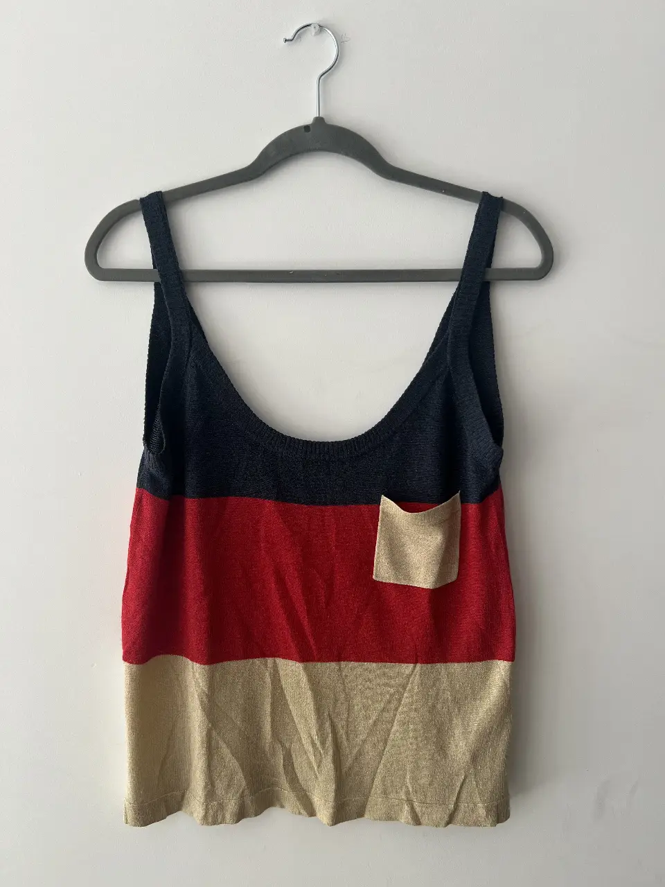 Musculosa de mujer con diseño tricolor en azul, rojo y beige. Cuenta con un bolsillo en la parte delantera y tirantes anchos. Ideal para un look casual y fresco.