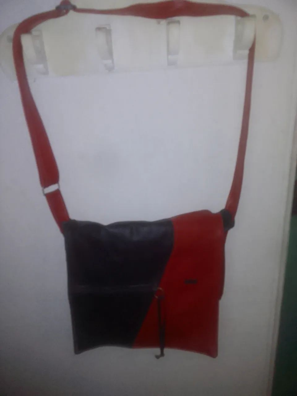 Bandolera de cuero sintético en dos colores, negro y rojo. Ideal para llevar tus esenciales con estilo. Cuenta con una solapa y correa ajustable.