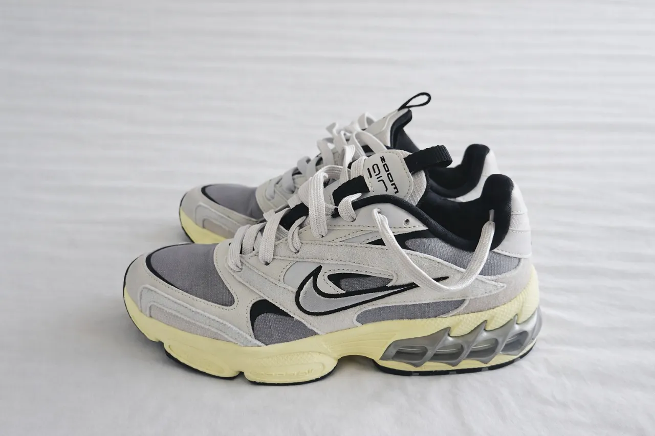 Zapatillas deportivas Nike color blanco y gris con detalles en negro y suela amarilla. Cierre de cordones.