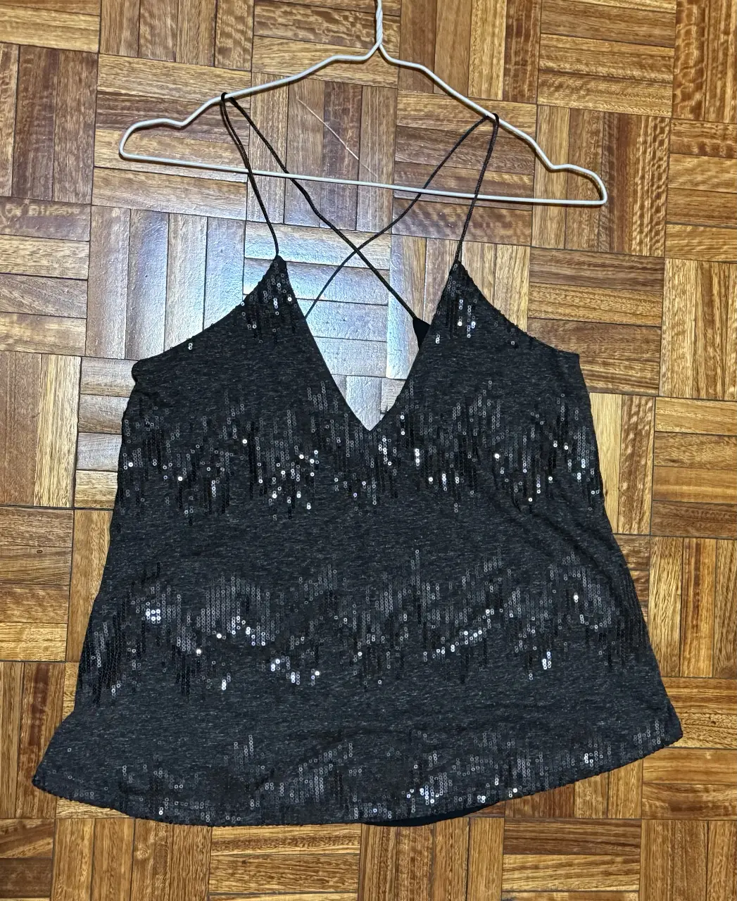 Top negro con lentejuelas, con tiras finas cruzadas en la espalda y escote en V. Ideal para fiestas y eventos.