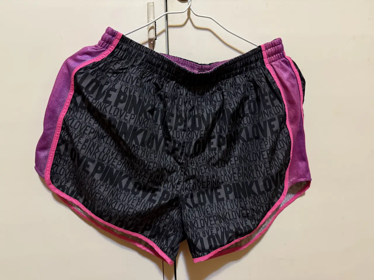 Short deportivo de mujer, negro con estampado "PINK LOVE" en gris. Detalles en rosa en los bordes y cintura. Ideal para actividades deportivas.