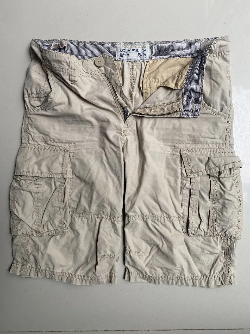 Shorts de gabardina color beige, estilo cargo con múltiples bolsillos. Cuentan con cierre y botón, y un diseño moderno y funcional, ideal para un look casual y cómodo.