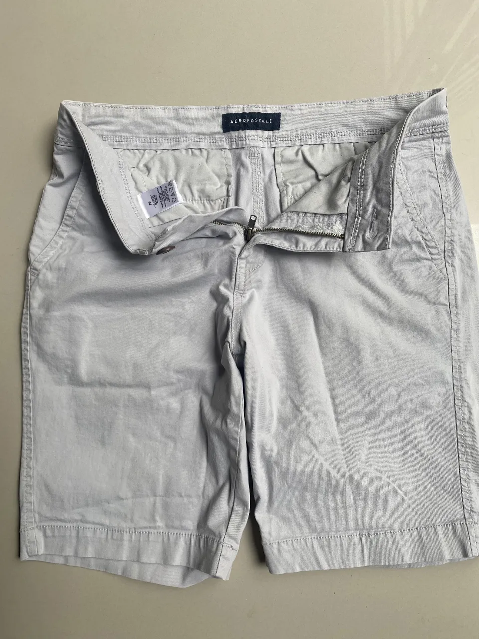 Bermudas de gabardina color gris claro, tiro alto, con cierre y botón. Ideales para un look casual de verano.