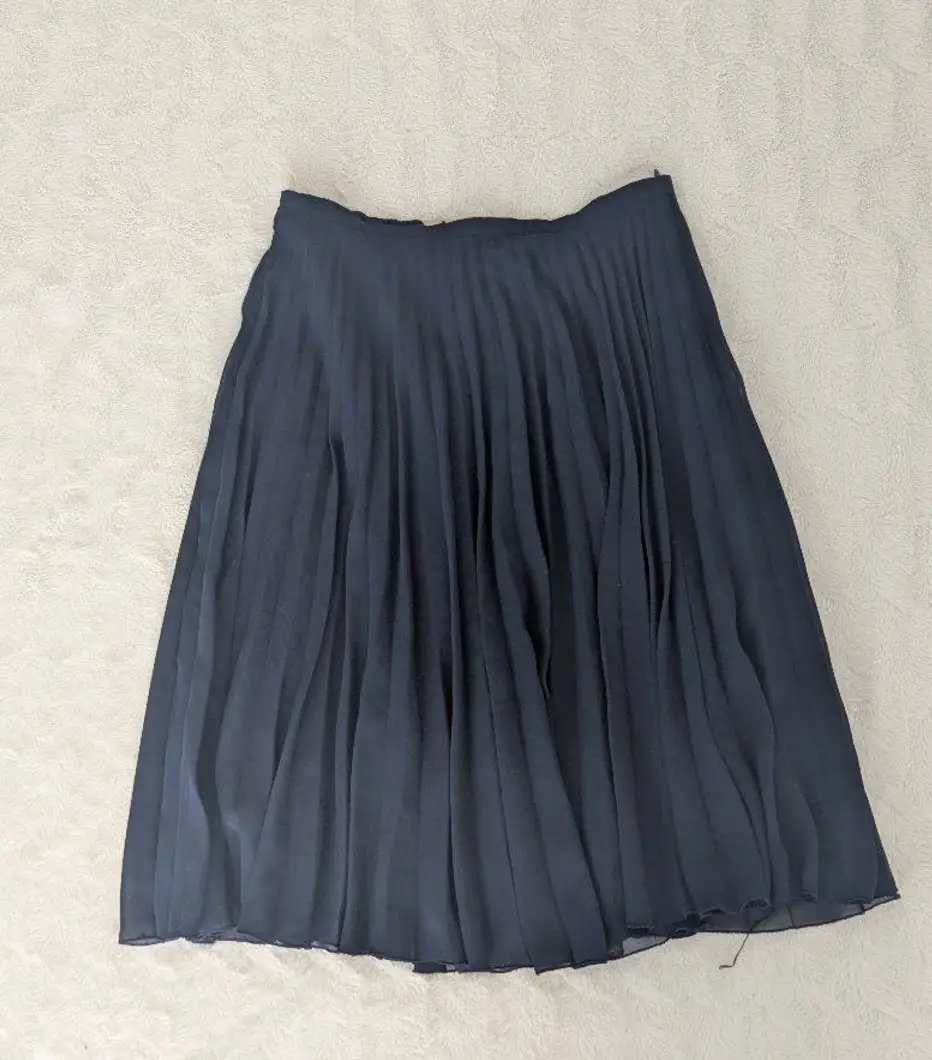 Pollera midi plisada de color azul marino, ideal para un look elegante y versátil. Confeccionada con un tejido ligero y fluido, no trasluce.