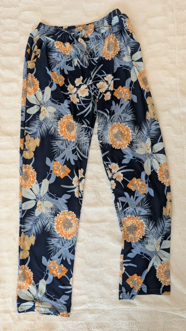 Pantalón suelto de mujer con estampado floral en tonos azul marino, naranja y celeste. Elastico en la cintura.
