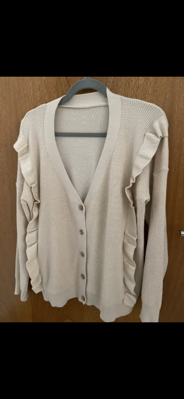 Cardigan de punto color crudo con detalle de volados en los bordes. Ideal para un look casual y cómodo. Es abrigado