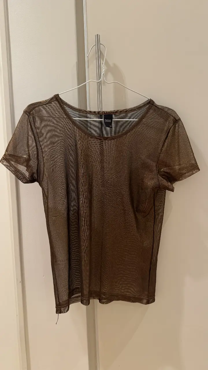 Remera de manga corta de malla transparente en color marrón. Ideal para un look moderno y audaz. Perfecta para combinar con otras prendas y crear diferentes estilos.