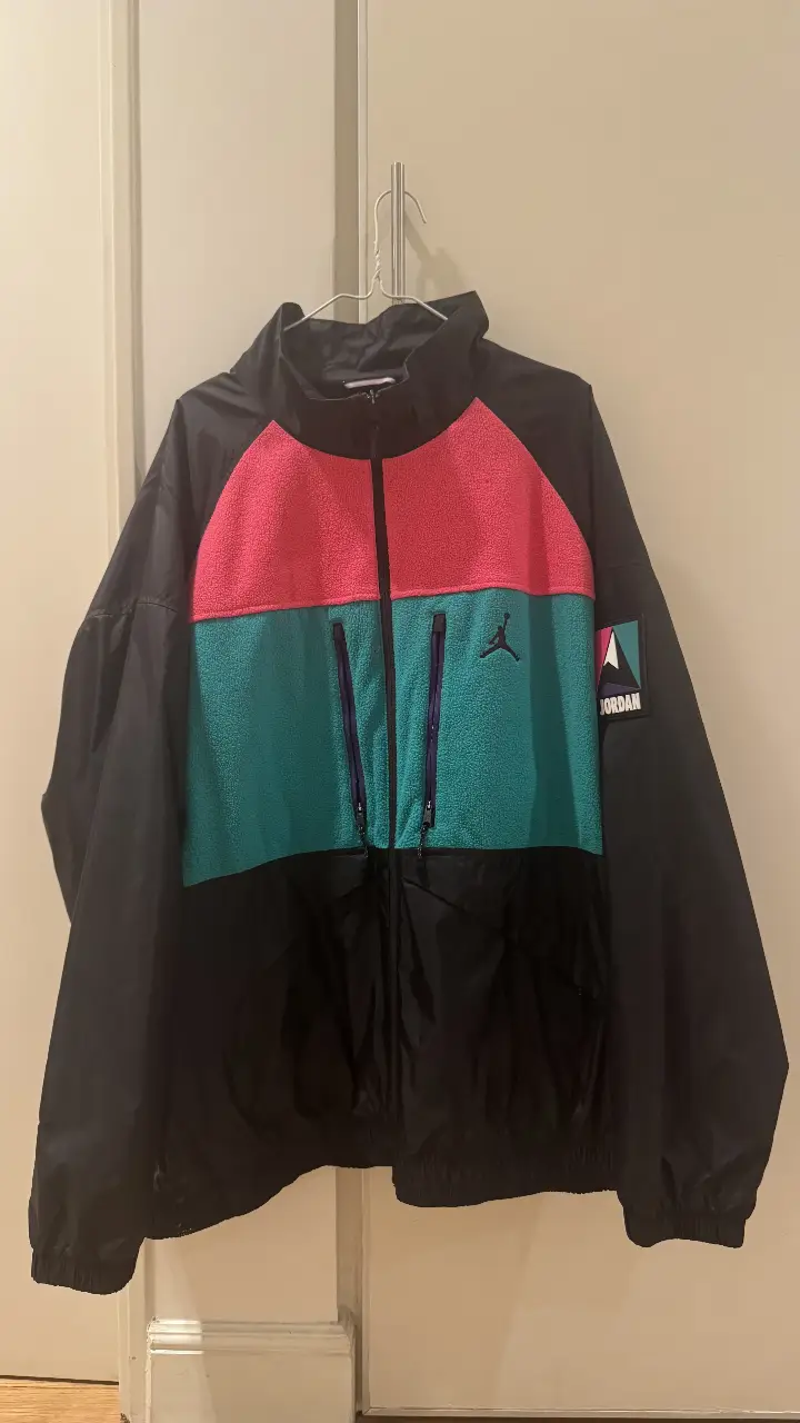 Campera Jordan de hombre, con diseño en bloques de color rosa y verde turquesa. Posee cierre completo y dos bolsillos frontales con cierre. Ideal para un look deportivo y urbano.