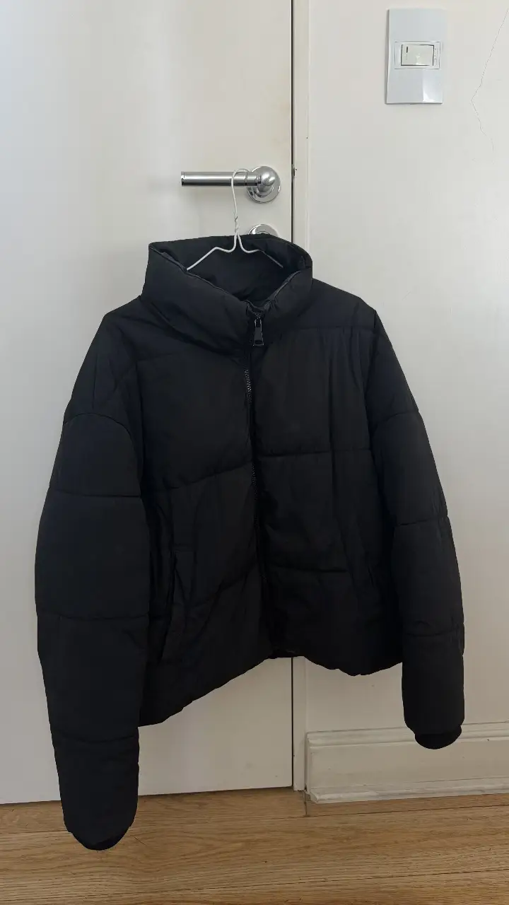 Campera puffer negra, ideal para el invierno. Con cuello alto y cierre frontal. Perfecta para un look casual y abrigado.