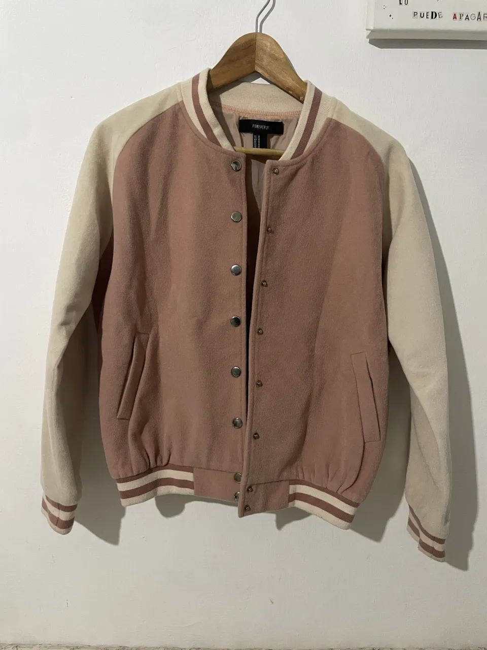 Campera bomber de estilo universitario, color rosa pálido y beige. 