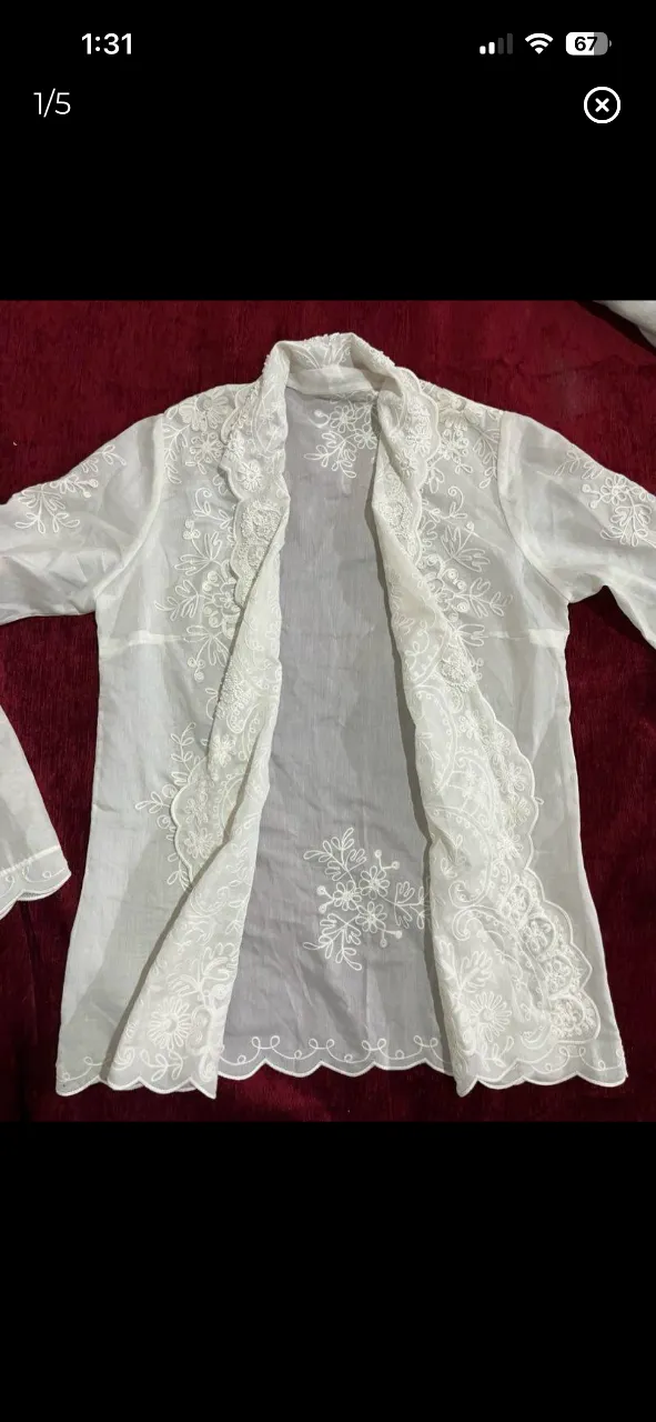 Blusa blanca de organza con bordados florales y detalles de pedrería en el cuello y puños. Diseño delicado y elegante, ideal para ocasiones especiales o para darle un toque sofisticado a tu look. Manga larga y corte abierto. la tela es bien finita y fresca