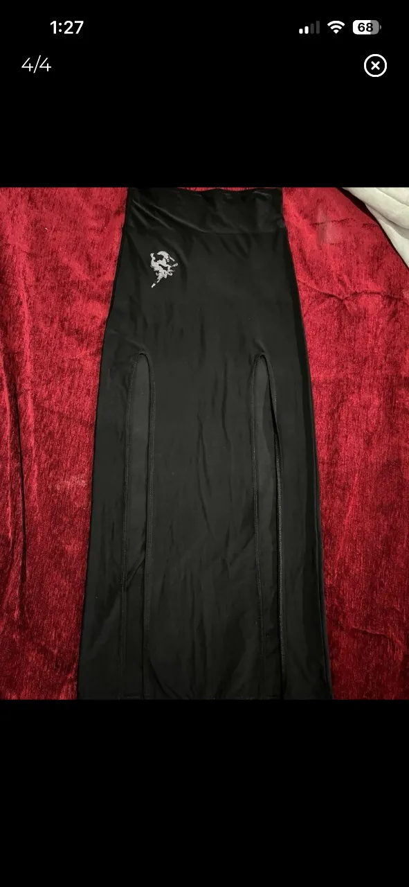 Pollera larga negra con dos tajos súper pronunciados. Tiene un estampado pequeño en la parte superior izquierda. Ideal para un look audaz y moderno.