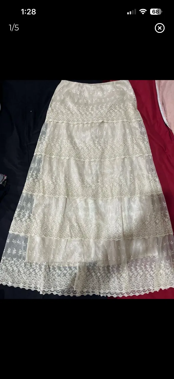 Pollera larga de encaje blanca, con múltiples capas y detalles florales bordados. Ideal para un look romántico y delicado.