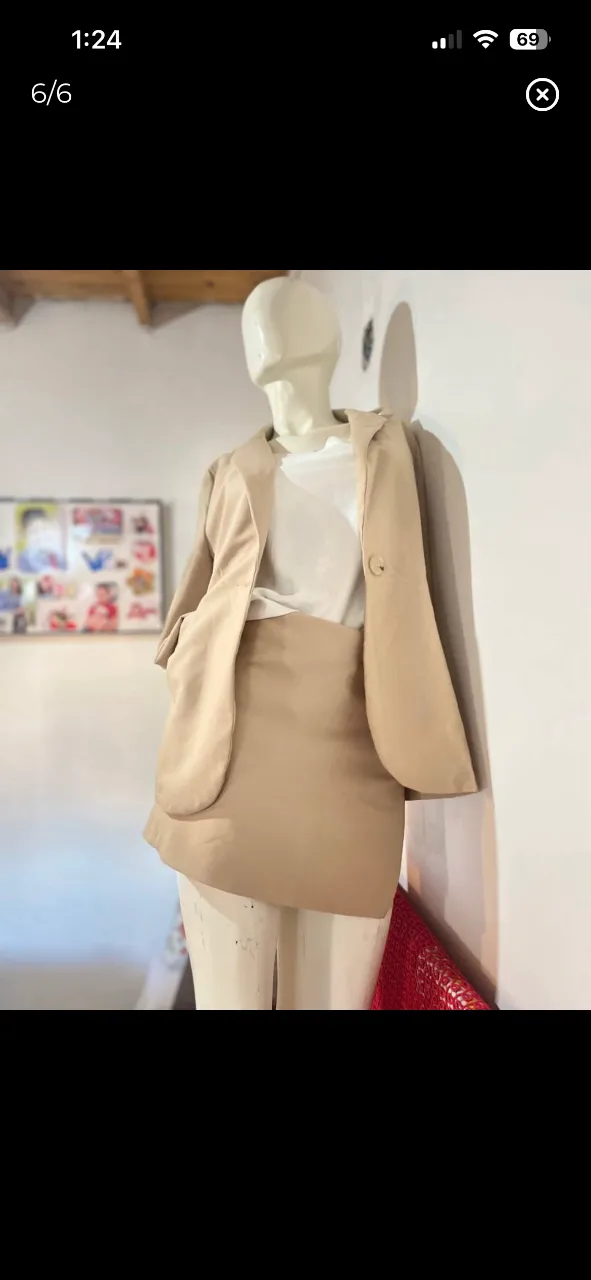 Conjunto de blazer y falda color beige. El blazer es de corte clásico con un botón y bolsillos. La falda es corta y de tiro alto. Ideal para un look elegante y profesional.