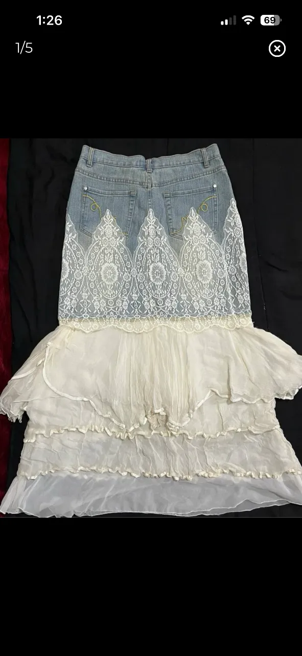 Pollera de jean intervenida con encaje blanco y volados de tela vaporosa. Un diseño único y bohemio, ideal para destacar tu estilo. Alberto Makali